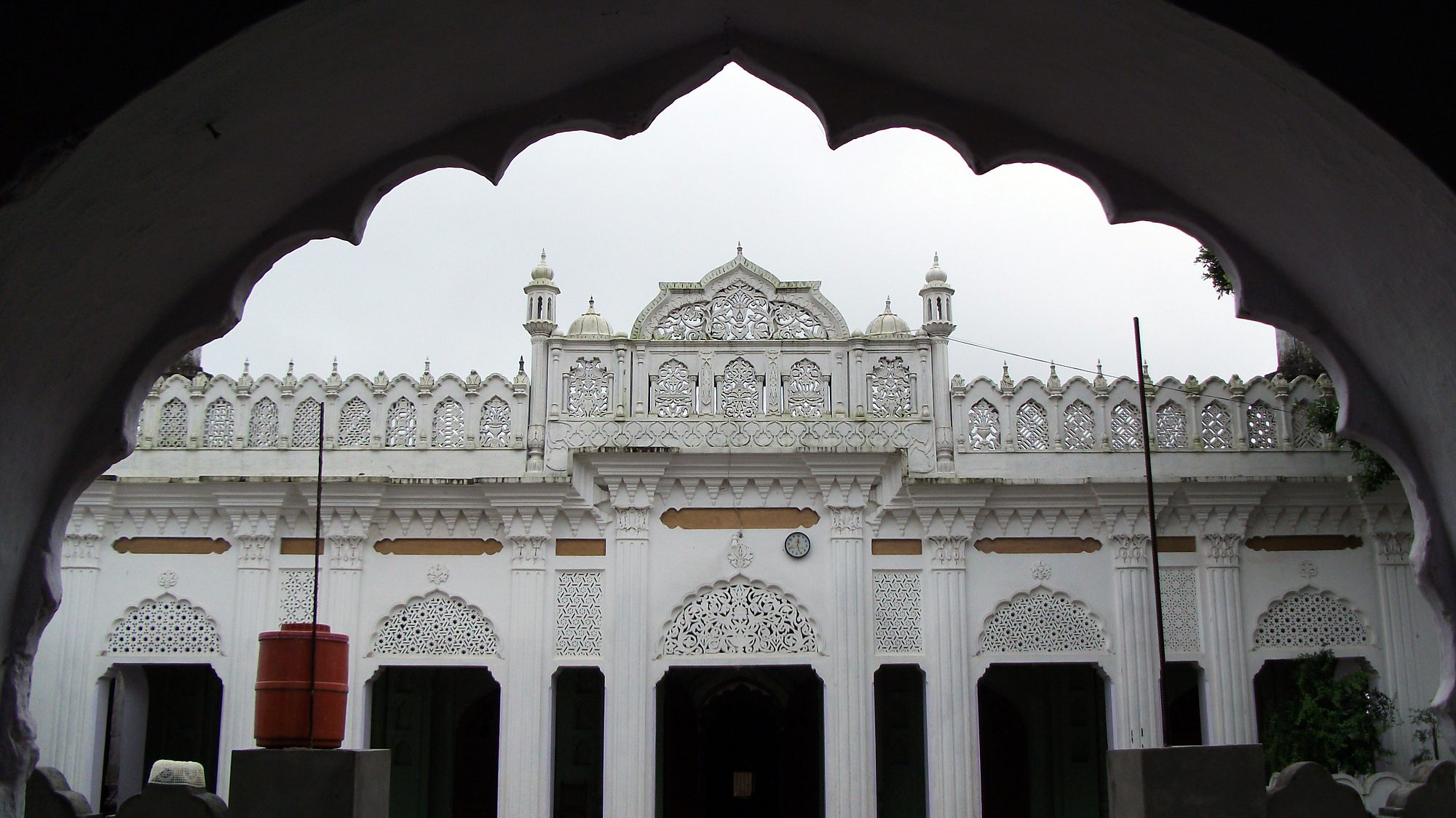 The mosque façade of Siraj-ul-Uloom seen through the campus gateway arch